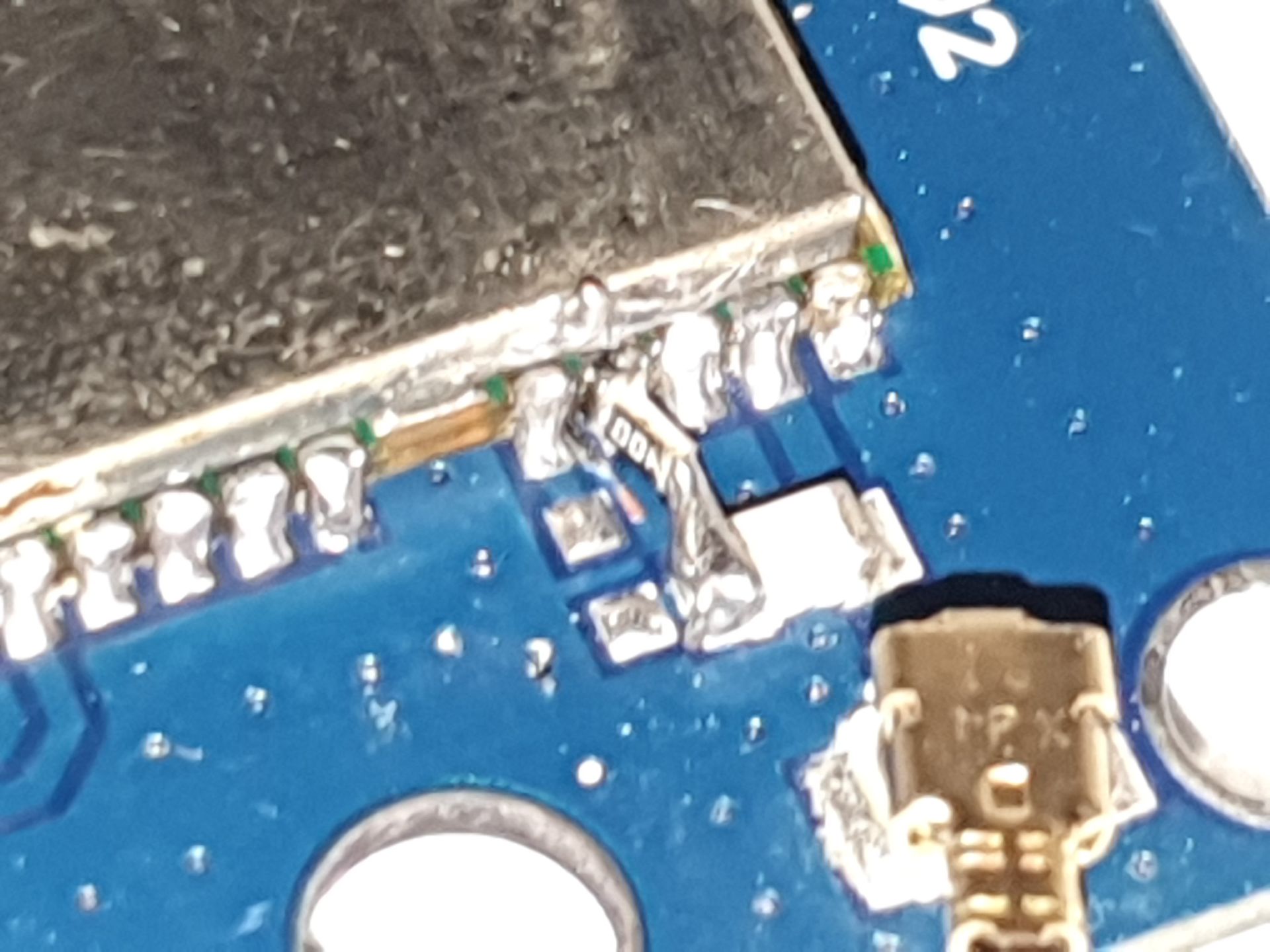 A close up of the repositioned resistor that is connected and held in place using moderately long solder bridges. Some scratch marks from cutting the track under the GPS module can also be seen.
